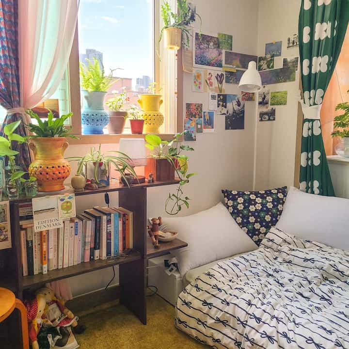 Warm natural-toned 6-tatami studio bedroom featuring diverse plants on the windowsill and shelves, creating a bright cozy space