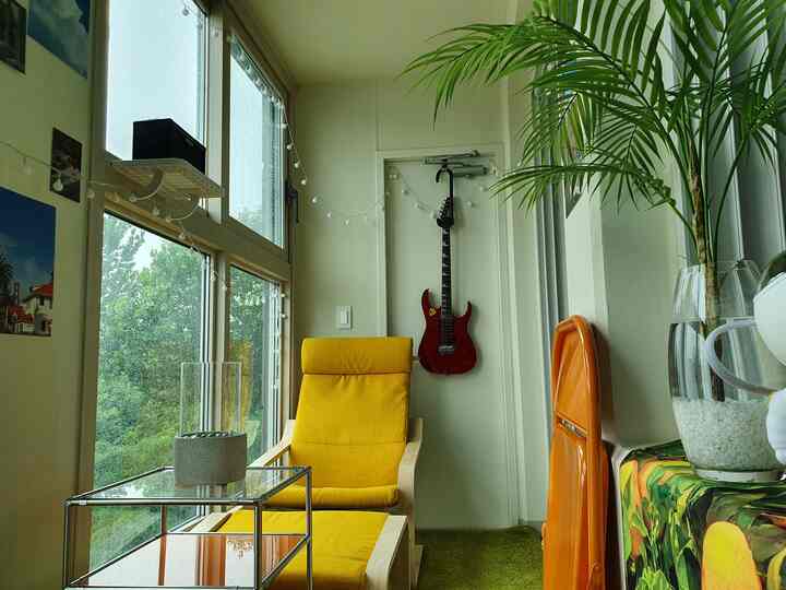 Natural color and yellow toned veranda space featuring a yellow armchair and string lights for a cozy atmosphere