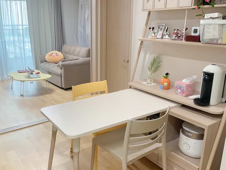 白と木目調が調和した二人暮らしのダイニングルーム、ソファとおうちカフェの設備が配置された雰囲気のあるインテリア