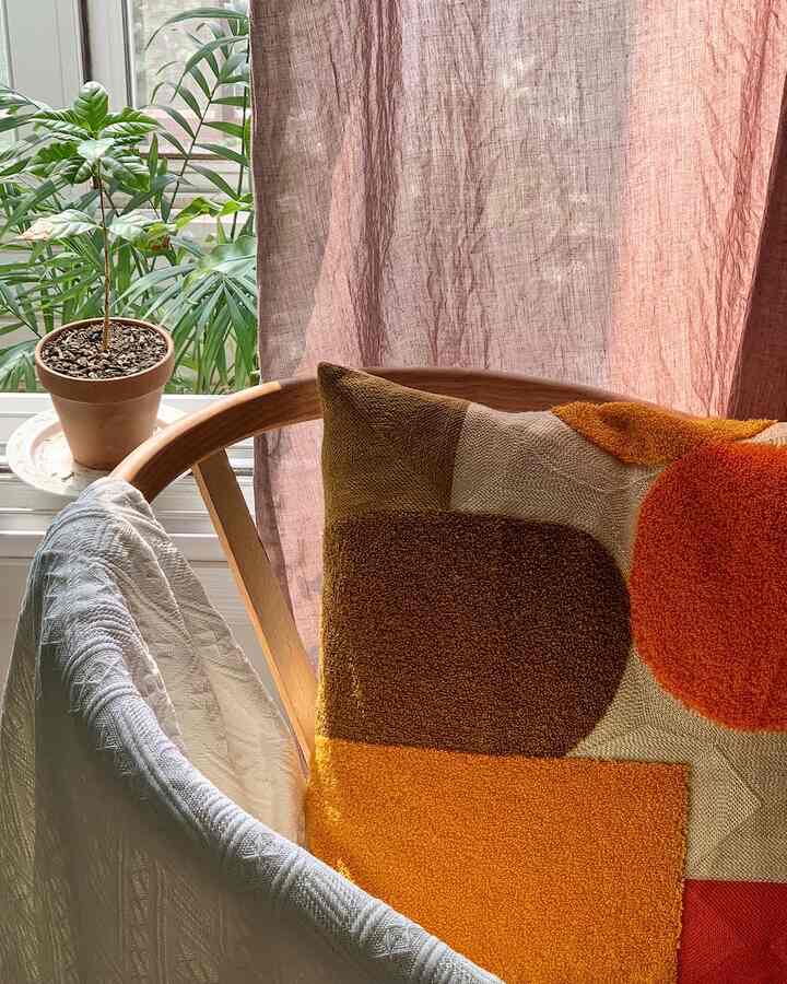 Natural space featuring warm wood tones, terracotta-colored curtain, and patterned cushion