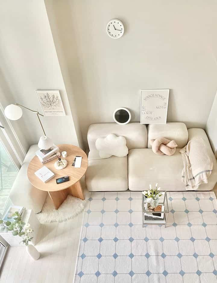 白と木目調が調和したリビング、シンプルモダンなソファと丸いサイドテーブルが配置された抜け感のある空間