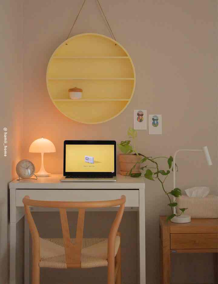 Cozy home office space featuring a yellow circular shelf, white desk, and wooden chair