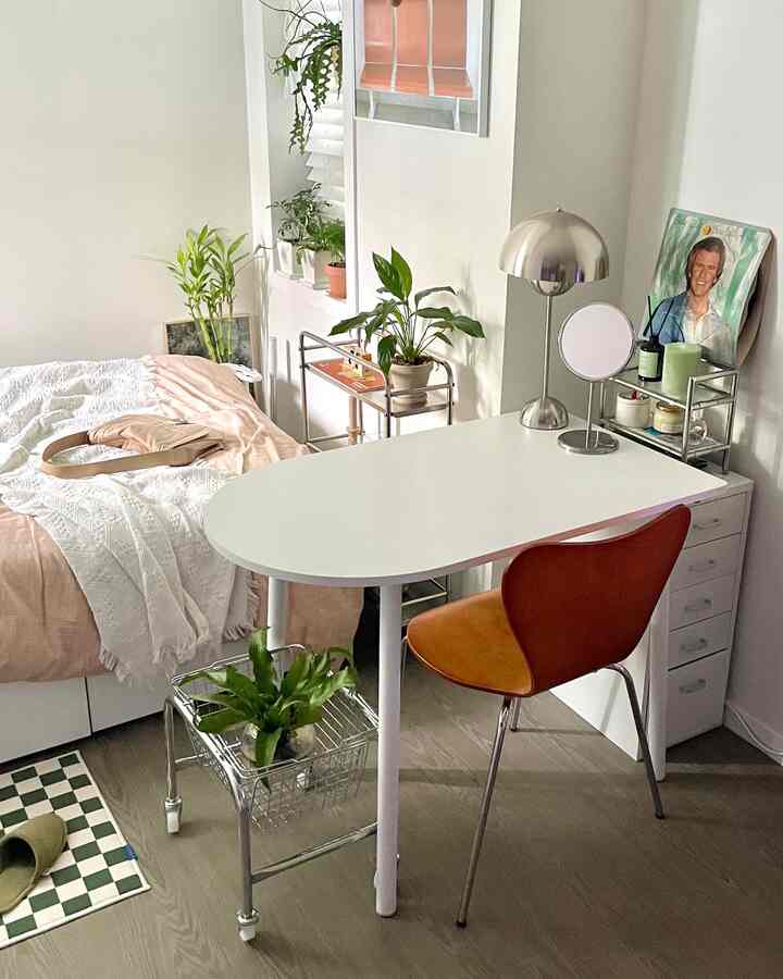 White and natural tone studio bedroom featuring a half oval table and plants creating a cozy atmosphere
