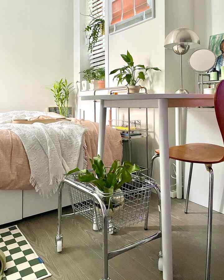 A minimalist single bedroom in white and wood tones featuring a desk and green plants