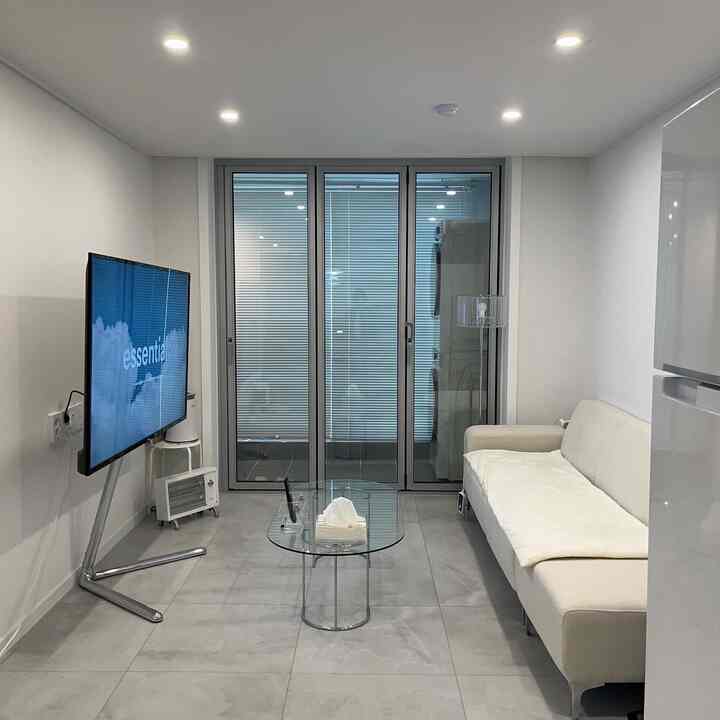 白を基調としたリビング、超スリム折戸と透明なガラステーブルが配置された、すっきりとしたミニマルなインテリア空間