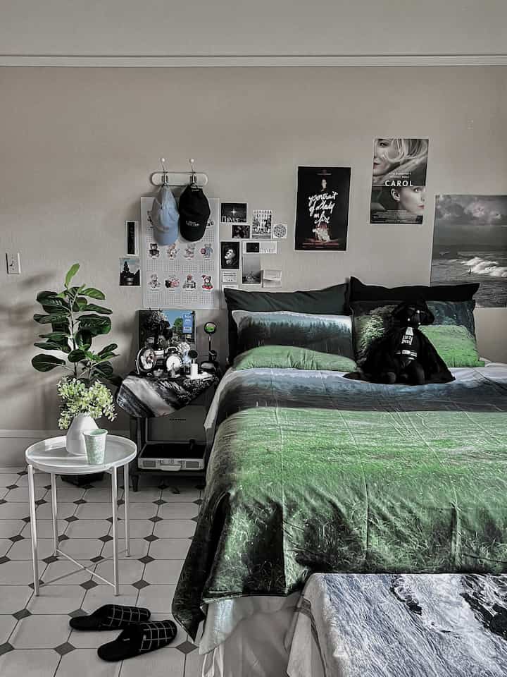 Natural modern bedroom featuring green bedding and posters with a calm, cozy atmosphere