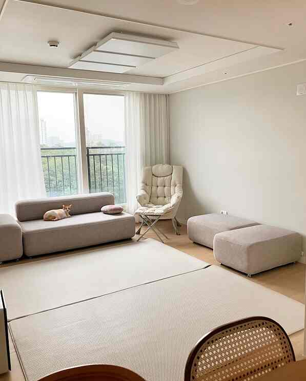 Beige and natural toned living room featuring a beige sofa, armchair, and ottomans with a clean, modern atmosphere