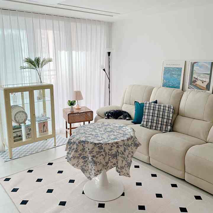 明るい白とナチュラル色調のリビング、クリーム色のソファと丸テーブル、犬がいるシンプルモダンな空間