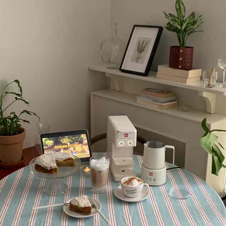White and natural tone living room table featuring coffee machine and cake in a cozy home cafe setting