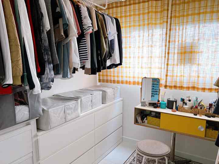 Compact wardrobe room featuring yellow check linen curtains, white dresser, and vanity with organized storage