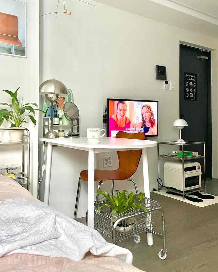 白と茶色の色調のリビング、丸テーブルと椅子、ステンレス製の収納設備が整然と配置された居心地の良いインテリア