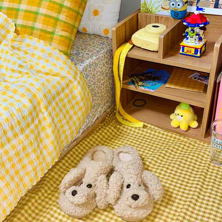 温かみのある黄色のチェック柄が特徴の寝室、犬の形のスリッパと木製の棚が印象的な雰囲気のあるインテリア