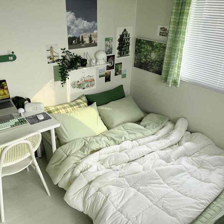 Green and white toned studio bedroom featuring neat desk and comfortable bedding with a cozy atmosphere
