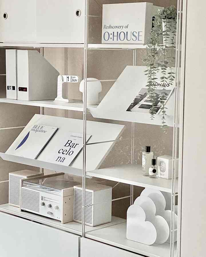 White and natural tone system shelf in a neat study space featuring minimal storage and decorative arrangements