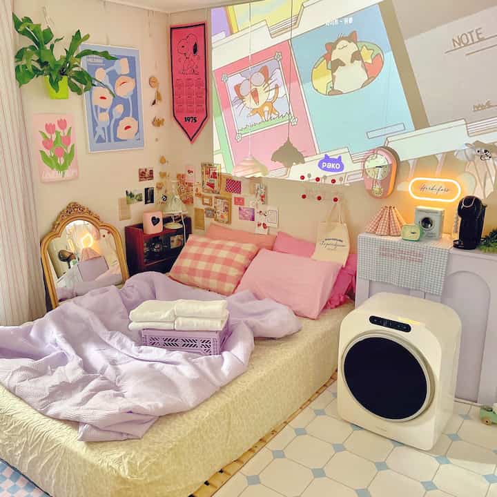 Light pink and light brown toned bedroom featuring a bed with pink pillows and towels, wall projection creating a home cinema atmosphere
