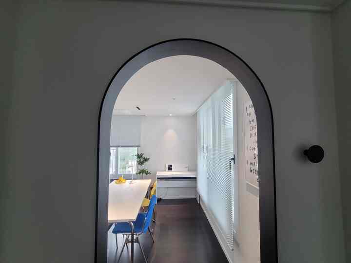 A white and black balanced dining room featuring yellow and blue dining chairs, minimalistic and modern space