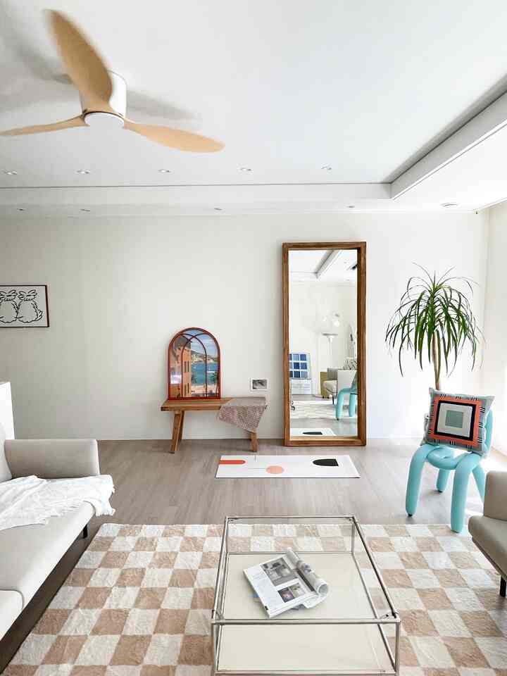 Light brown and white toned living room featuring a full-length wooden mirror and natural wooden bench with a simple, natural atmosphere