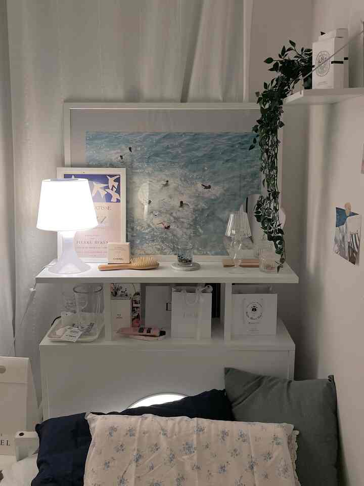 白とネイビーのトーンのリビング、ソファベッドとテーブルランプ、ポスターが配置された印象的な空間