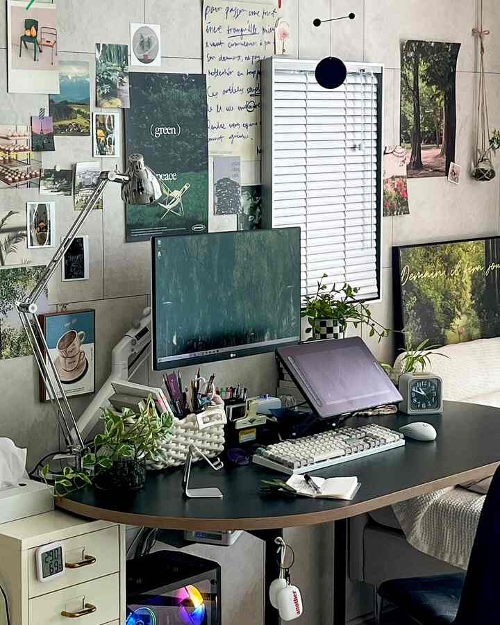 Black and white tone home office space featuring monitor, posters, and plants creating a cozy work environment