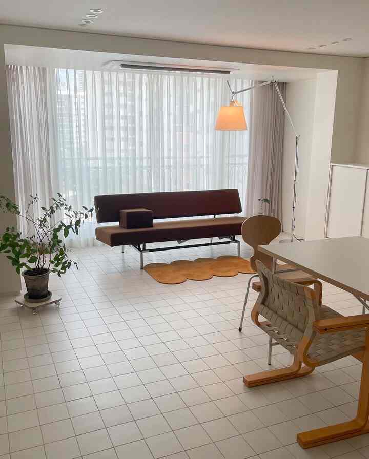 白いタイルの床とシンプルな家具が配置された明るくミニマルなリビング・ダイニング空間