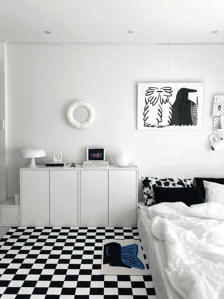 白と黒のモノトーンの寝室、チェッカーボードラグと整った寝具が配置されたシンプルな室内