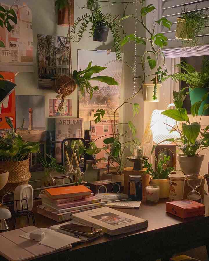 Cozy desk space featuring warm lighting and abundant plants