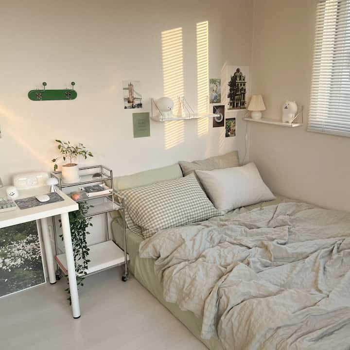 ミント色の寝具と白い壁の棚が配置された、落ち着いた雰囲気のある自然な印象の寝室