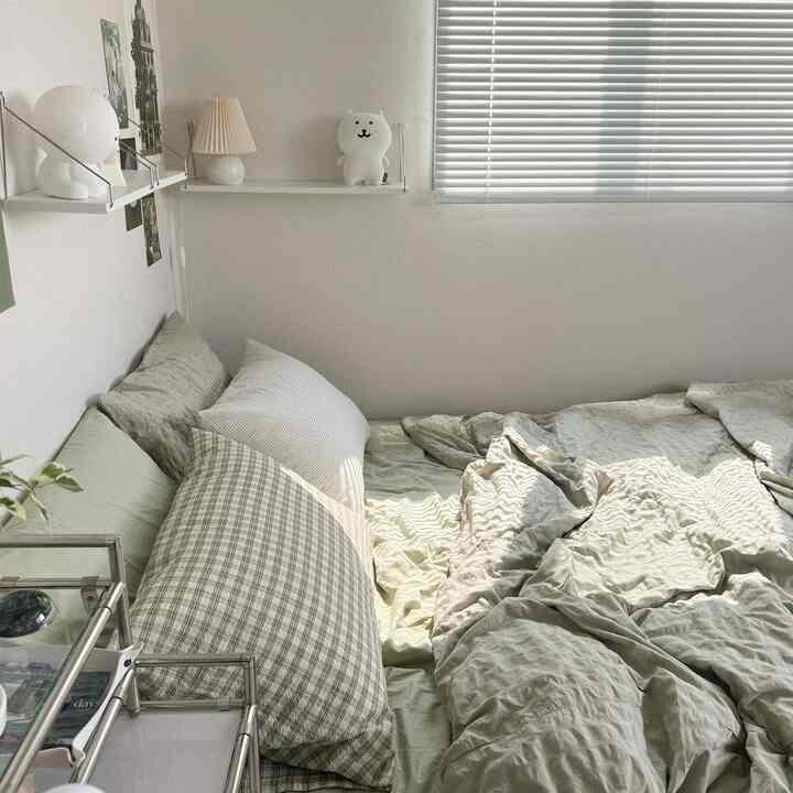 Natural toned bedroom featuring cozy bedding and cushions with white blinds, creating a serene atmosphere
