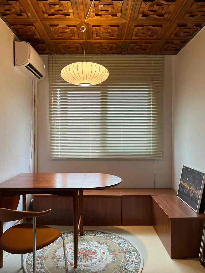 暖かいウッドトーンとベージュのダイニングルーム、木製ダイニングテーブルと椅子、ペンダントライトとブラインドが調和した雰囲気のあるインテリア