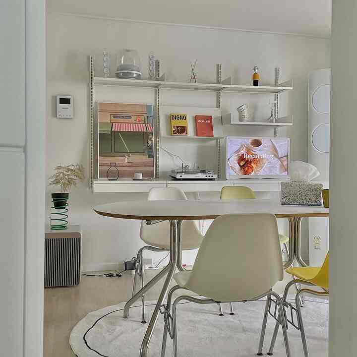 白とベージュの色調のダイニング、丸テーブルと椅子、壁棚が配置された雰囲気のあるシンプルな空間