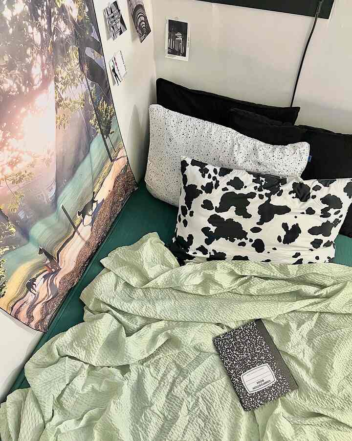 Cozy studio bedroom featuring green mattress with light green duvet cover and black-white pillows