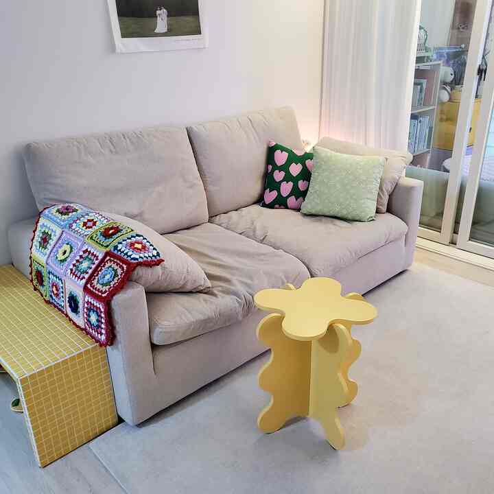 白とベージュのトーンのリビング、快適なベージュのソファとカラフルなクッションが配置された印象的な空間