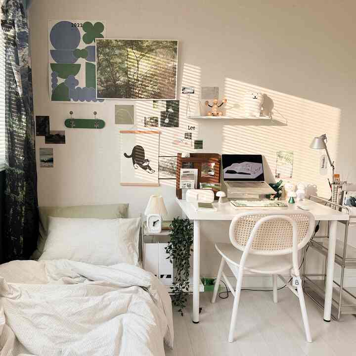 Warm natural-toned studio bedroom and home office with white furniture and green plants creating cozy atmosphere