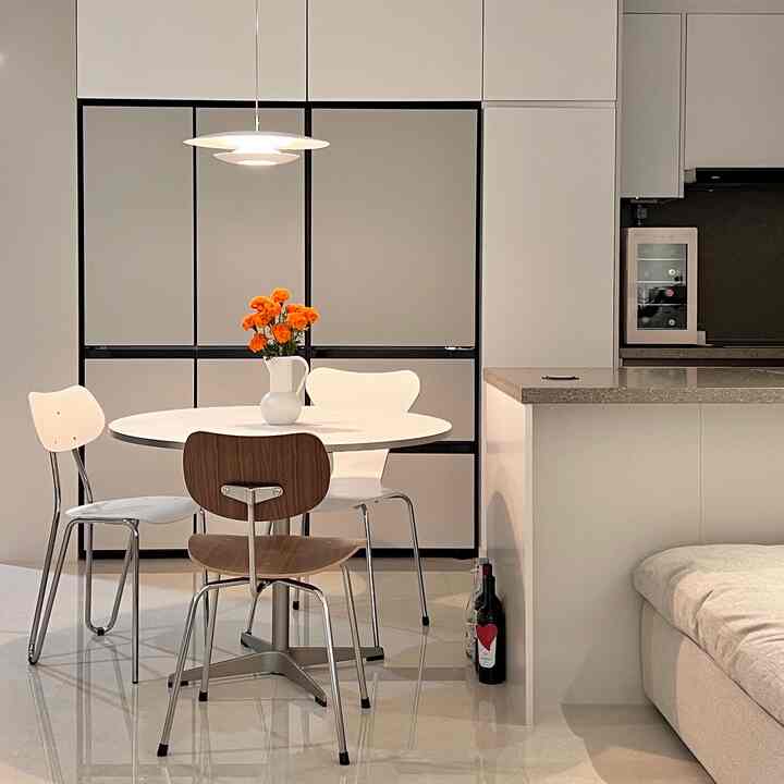 白と木目調が調和するキッチン、丸いダイニングテーブルとペンダントライトが配置されたシンプルでナチュラルなインテリア