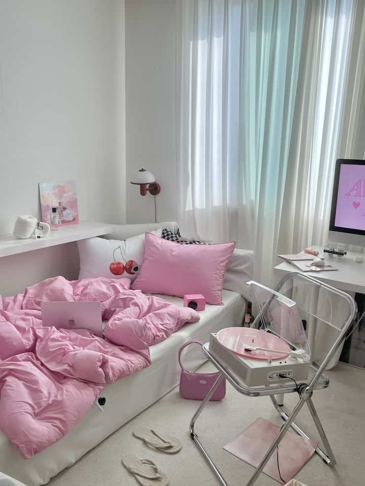 Pink and white toned bedroom featuring neat bedding and a home office setup, creating a cozy atmosphere