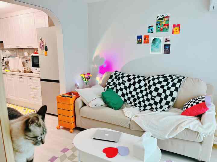 Modern living room with white walls featuring an ivory sofa adorned with checkerboard blanket and cushions in a cozy setting