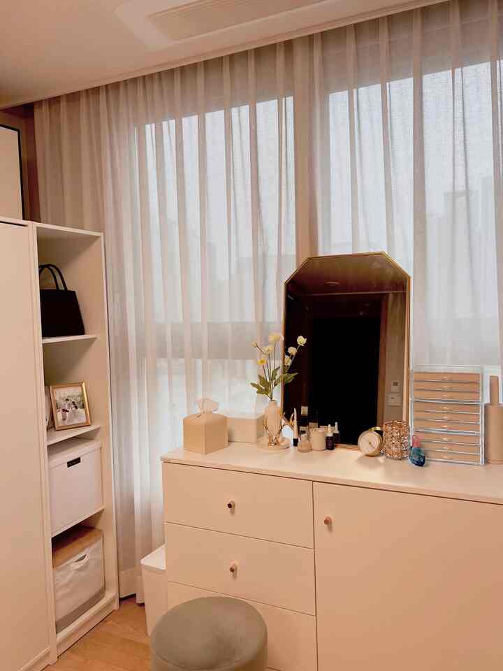 A white and natural toned walk-in closet featuring a vanity and wardrobe arranged neatly in a cozy space