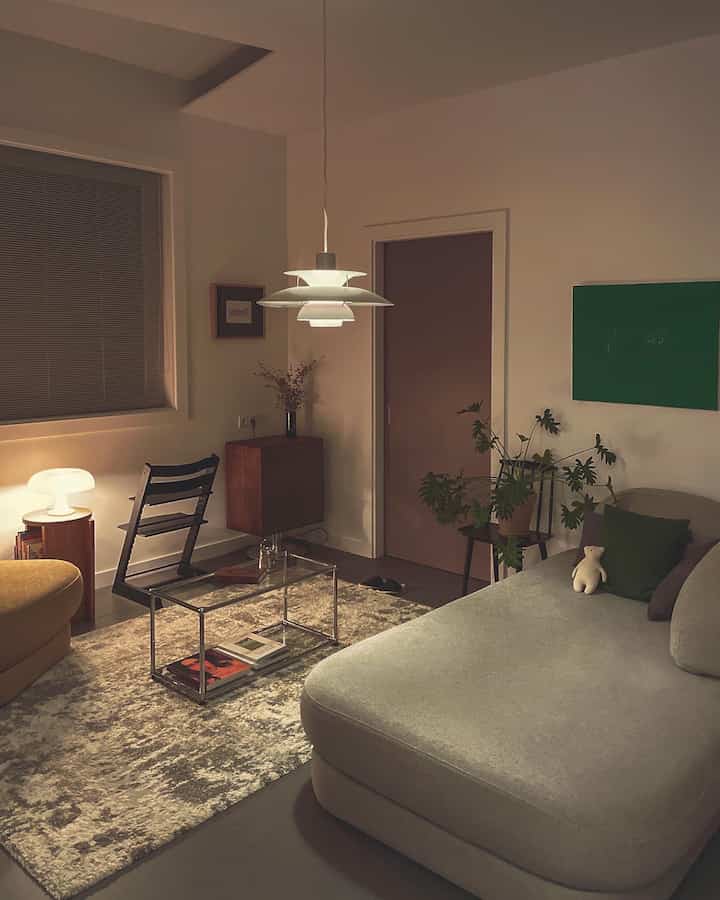 ベージュとブラウンの色調のリビング、ペンダントライトとソファ、植物が配置された落ち着いた雰囲気のあるインテリア