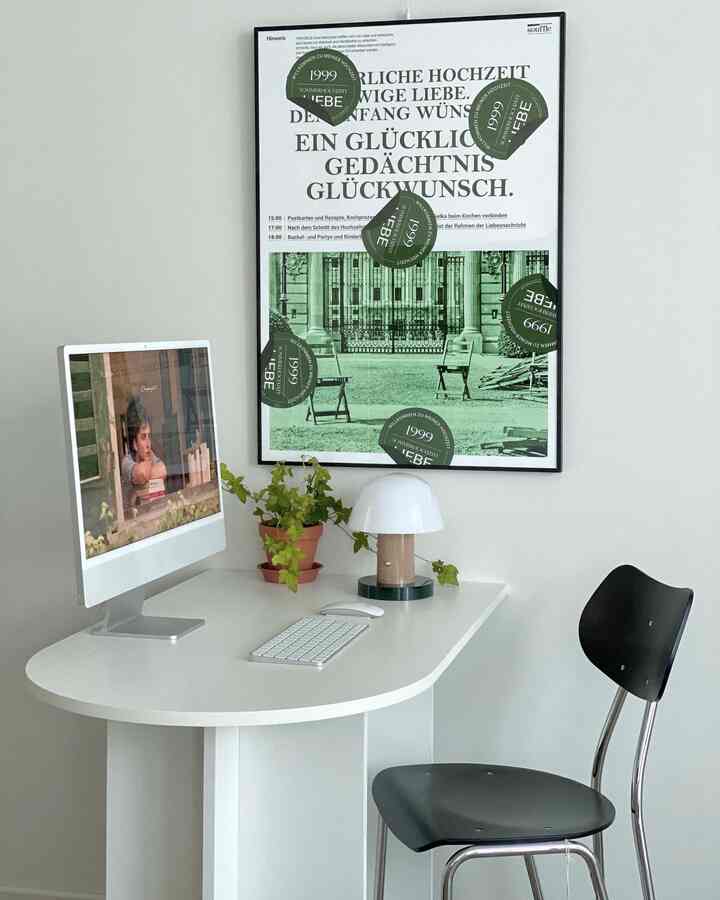 Minimalistic white and black home office space featuring desk with computer, plant, and chair arranged neatly