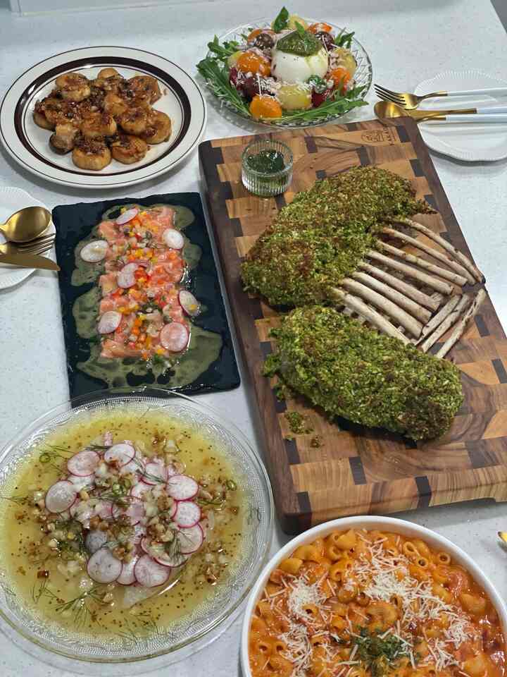 白いテーブルの上に多彩なホームパーティー料理と皿、ボウルが並べられたダイニング空間