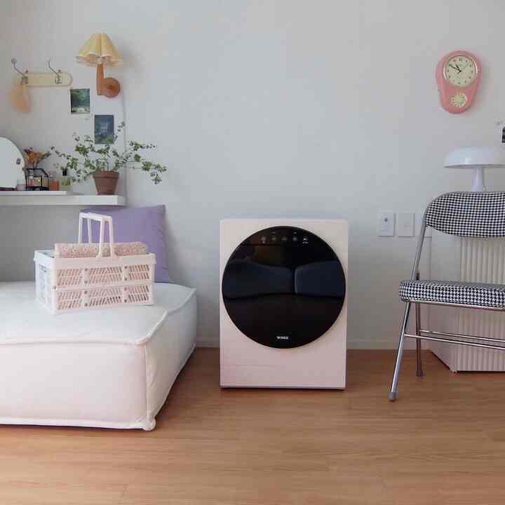 A clean living room in white and wood tones featuring a compact Winix mini dryer and simple furniture