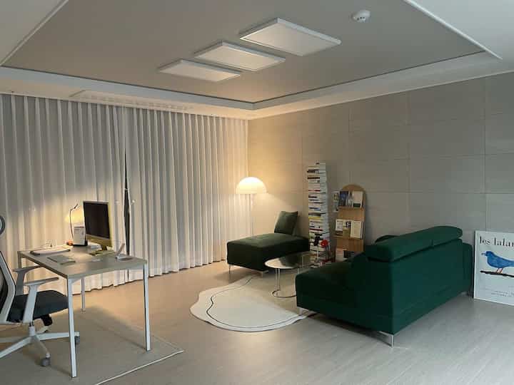 White and green toned home office and living room study space featuring modern layout with comfortable sofa seating