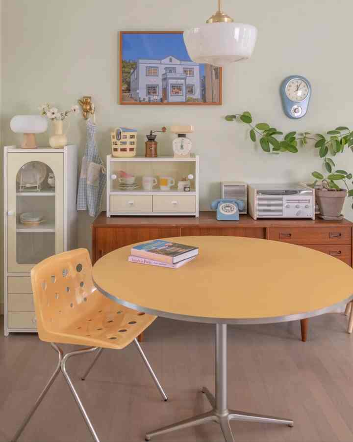 黄色と茶色のトーンが特徴のダイニングルーム、丸テーブルとヴィンテージ小物が調和した雰囲気のある空間