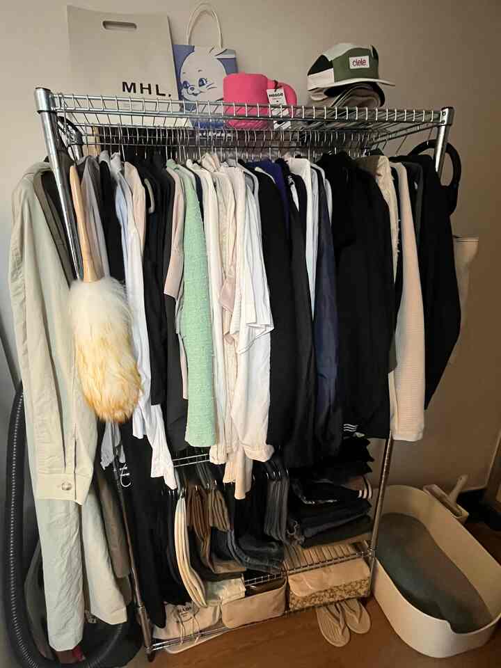 Natural toned floor compact space with metal clothes rack, featuring clothing and a cat litter box for practical storage