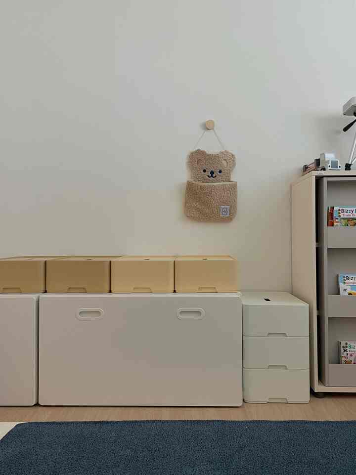 Minimal kids' room in white and beige tones, featuring neat toy storage boxes and bookshelves