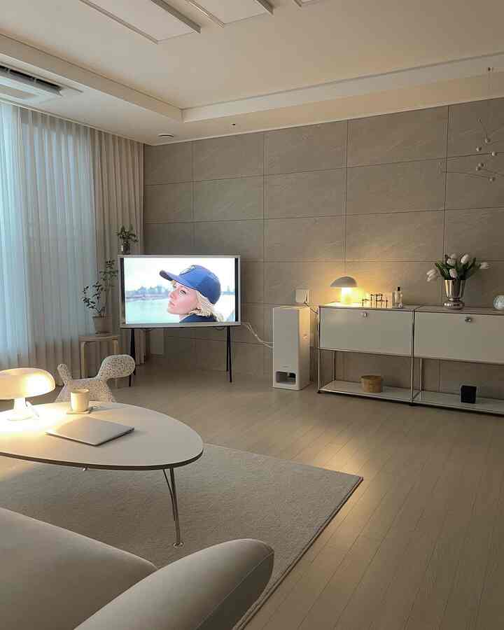 Bright natural-tone modern living room featuring white sofa, coffee table, TV stand, and warm table lamps with a clean atmosphere