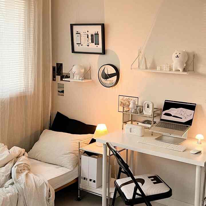 Warm white-toned small bedroom and home office space featuring a desk, bed, and mood lamps arranged cozily