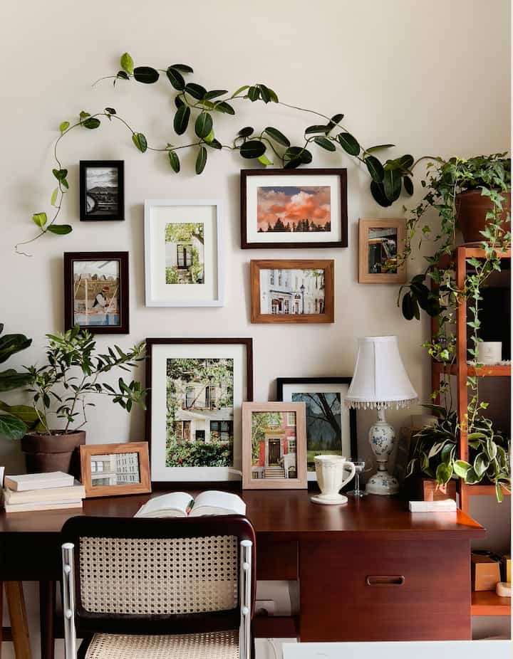 ベージュの壁と茶色い木製家具が調和した書斎、額縁と多くの植物が配置されたナチュラルなワークスペース