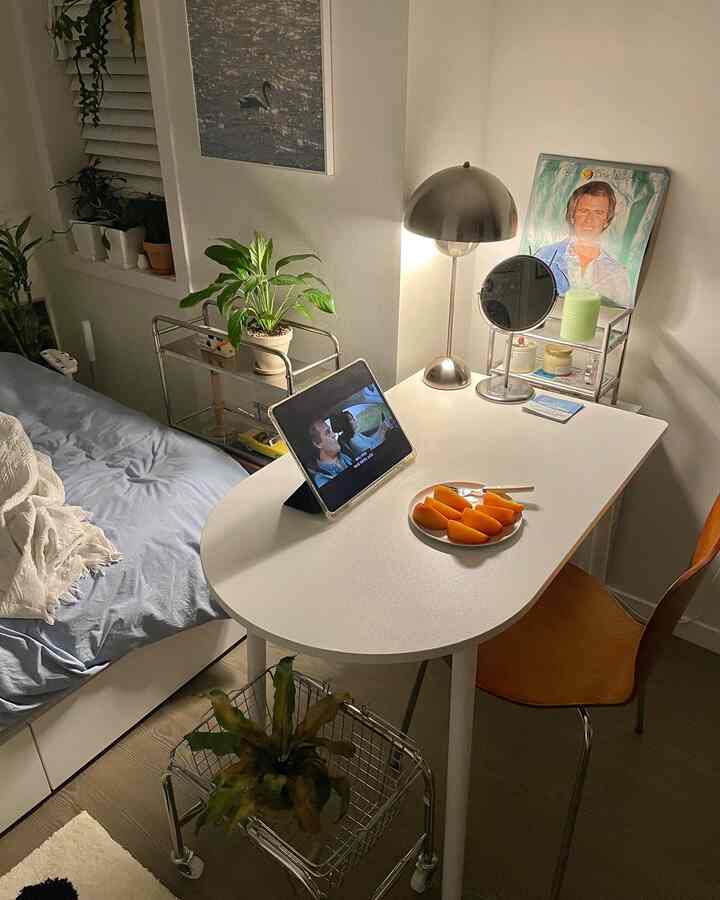 ナチュラルな色調のワンルーム、ラウンドテーブルとフロアランプ、複数の植物とiPadが配置された雰囲気のある空間