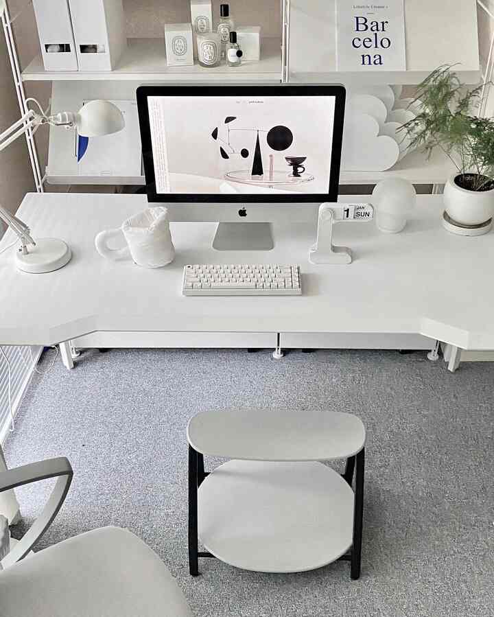 White and gray toned home office featuring a spacious desk, modern stool, and organized shelves creating a comfortable workspace